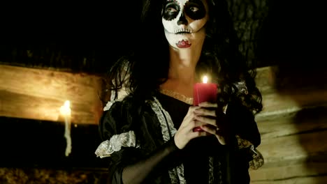 Young-woman-with-scary-skeleton-Halloween-make-up-holding-a-lighted-candle.-HD