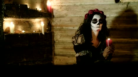 Young-woman-with-scary-skeleton-Halloween-make-up-holding-a-lighted-candle.-HD