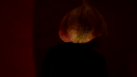 Scary-man-with-a-pumpkin-head-and-luminous-eyes-looks-at-the-camera.-Man-with-a-pumpkin-head-scares-raising-his-hands-up.-Halloween.