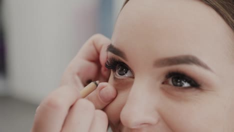 Professionelle-Make-up-Künstler-Frau-malt-Wimpern-an-Kunden-des-Schönheitssalons