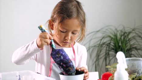 Niña-pequeña-replantar-una-flor-en-casa,-en-el-interior