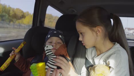 Chica-jugando-con-niño-pequeño-durante-el-paseo-en-coche