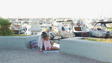 Frau-mit-Tochter-lesen-Karte-im-Hafen-von-Forio