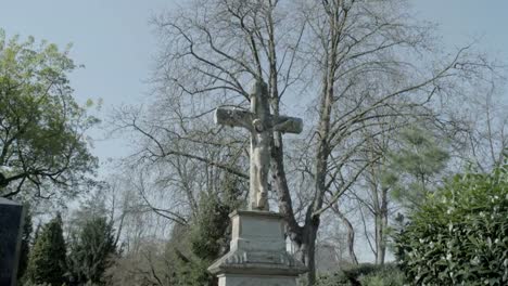 Old-tombstone-with-Jesus-cross-on-a-sunny-spring-day.-Tilt-from-sky-to-tombstone.-4K-in-SLOG3.-Long-shot.