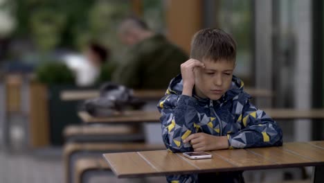 niño-durmiendo-sentado-en-una-mesa-en-un-café-al-aire-libre,-las-palomas-de-fondo