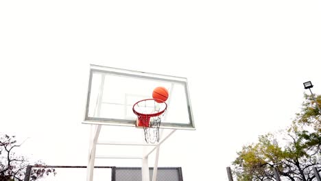 Young-man-throwing-basketball-ball-on-court-in-park-successfully,-slow-motion-shot