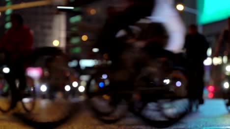 Lot-of-cyclists-ride-during-night-cycling-bike,-bicycle-parade-in-blur-by-illuminated-night-city-street-timelapse.-Crowd-of-people-on-bike.-Bike-traffic.-Concept-sport-healthy-lifestyle.-Bright-shining-lights.-Low-angle-view