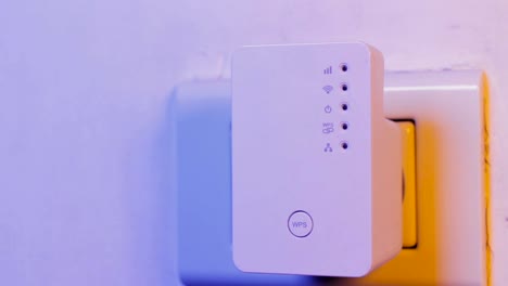 Menschen-drücken-mit-dem-Finger-auf-die-WPS-Taste-am-WLAN-Repeater-in-die-Steckdose-an-der-Wand