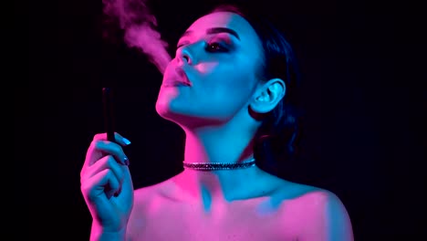 Gorgeous-brunette-woman-smoking-electronic-cigarette-in-neon-color-light