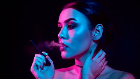 Hermosa-mujer-morena-fumar-cigarrillo-electrónico-en-luz-de-neón-color