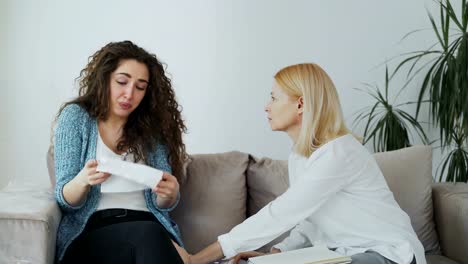 Llorando-tensionó-mujer-conversar-con-profesional-psicólogo-femenina-que-le-da-su-pañuelo-de-papel-para-enjugando-sus-lágrimas