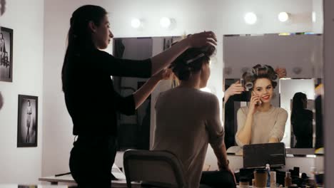 Woman-with-hair-curlers-calling-by-mobile-phone-front-mirror-in-dressing-room