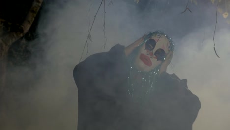 Maléfique-Halloween-lustige-Clown-trägt-eine-Maske-und-grün-gefälschte-Haare-Durchführung-eines-bösen-Tanzes-in-einem-dunklen-Wald