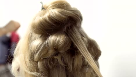 Hairdresser-makes-hairstyle-with-curling-iron-to-woman