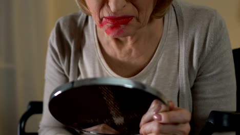 Old-woman-in-wheelchair-smearing-lipstick-over-her-face-and-hysterically-crying