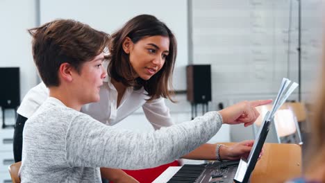 Male-Pupil-With-Teacher-Playing-Piano-In-Music-Lesson