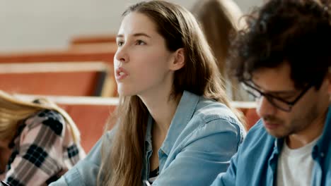 Portrait-Footage-of-Smart-and-Beautiful-Young-Girl-Listening-to-a-Lecture-in-a-Classroom-Full-of-Multi-Ethnic-Students.-Shallow-Depth-of-Field.