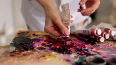 Artist-squeezes-the-paint-from-the-tube-on-palette