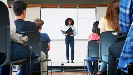 Lehrer-geben-Präsentation-zu-High-School-Klasse-vor-Bildschirm