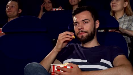 Palomitas-atractivo-joven-comiendo-durante-la-aburrida-película-en-el-cine