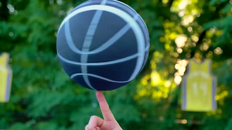 Basketball-spinning-and-balancing-on-one-finger-with-trees-in-background,-during-sunrise,-playing-in-park