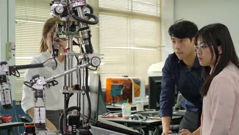 Team-of-robotics-engineer-works-with-robot,-assembling-and-testing-robotics-responses-with-laptop-Computer-in-workshop.-People-with-technology-or-innovation-concept.