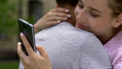 Girl-texting-on-smartphone-while-embracing-boyfriend,-lie-and-betrayal,-closeup