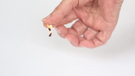 closeup-of-an-older-womans-hand-holding-a-burning-matchstick