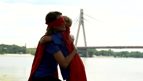 Mom-in-superhero-costume-kisses-son-forehead,-embracing,-support-in-beginnings