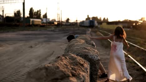 Picture-of-creepy-male-and-female-ghost-or-zombie-walking-with-wounded-face.-Male-zombie-climbing-on-blocks-on-the-ground.-Industrial,-abandoned-town,-raiways-around