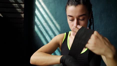 Cámara-lenta-forma-a-joven-en-el-piso,-envolver-las-manos-con-cinta-de-vendaje-preparación-para-entrenamiento-de-boxeo