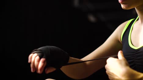 Closeup-panning-fit-woman-wrapping-hands-with-bandage-tape-preparing-for-boxing-training-slow-motion