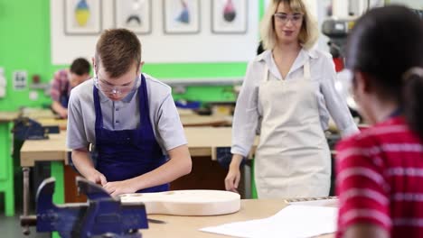 Female-Teacher-Helping-Male-High-School-Student-Building-Guitar-In-Woodwork-Lesson