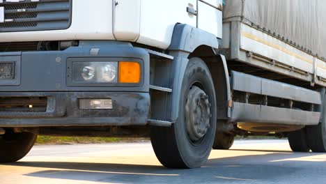 Räder-des-LKW-fahren-auf-Asphalt.-Kamera-zu-folgen,-LKW-fahren-auf-der-Autobahn.-LKW-Fahrten-durch-die-Landschaft-mit-schönen-Landschaft-im-Hintergrund.-Seite-Ansicht-Slow-Motion-hautnah