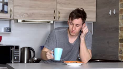 Beautiful-sleepy-man-having-breakfast-at-the-table