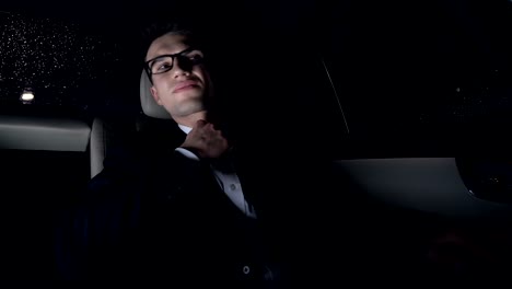 Nervous-businessman-sitting-on-back-seat-of-car,-anxious-about-work,-nighttime