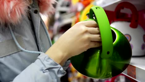 Eine-junge-Frau-wählt-einen-grünen-Stahl-Kessel-im-Supermarkt.