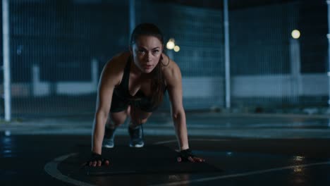 Beautiful-Sporty-Fitness-Girl-Doing-Push-Up-Exercises.-She-is-Doing-a-Workout-in-a-Fenced-Outdoor-Basketball-Court.-Night-Footage-After-Rain-in-a-Residential-Neighborhood-Area.