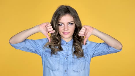 Young-Girl-Gesturing-Thumbs-Down-Isolated-on-Yellow-Background