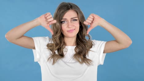 Junges-Mädchen-gestikulieren-Daumen-runter-auf-blauem-Hintergrund-isoliert