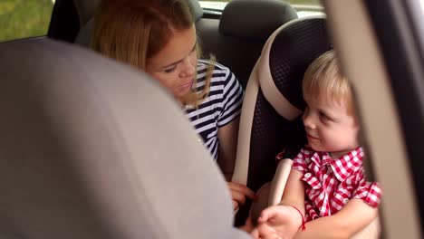 A-little-boy-sitting-in-a-car-seat,-sitting-next-to-his-mother.