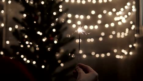 Wunderkerze-in-der-Hand-mit-feiern-Weihnachten-Lichter-Hintergrund