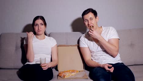 Glückliches-Paar-vor-dem-Fernseher-während-des-Essens-pizza