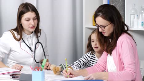 Una-mujer-con-una-hija-joven-hablando-con-un-pediatra-de-médico-en-la-oficina.