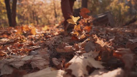 Man-is-stepping-on-ground-in-autumn-forest,-kicking-foliage,-close-up-of-feet