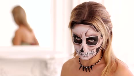 Junge-Blondine-mit-einem-Bouquet-von-schwarzen-Blumen-und-Make-up-in-Form-des-Skeletts.