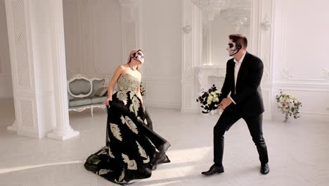 Couple-in-costumes-and-makeup-for-Halloween,-they-dance-in-a-bright-white-room