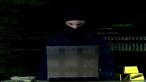 Criminal-in-balaclava-working-on-laptop,-hacking-bank-security-system,-data-code