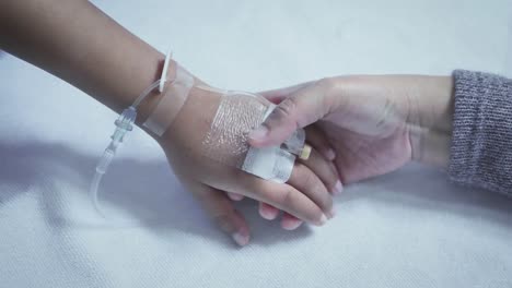 Mother-holding-hand-of-his-son-sick-bed-in-the-hospital.-Touch-the-hand-Slow-motion.-care-encouragement