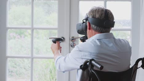 Senior-Disabled-Man-In-Wheelchair-At-Home-Wearing-Virtual-Reality-Headset-Holding-Gaming-Controller